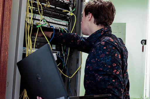 IT technician working with a laptop in a server room