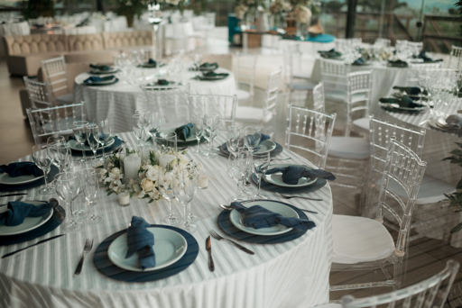 Wedding planner Strasbourg : illustration d’une salle de réception avec tables rondes, serviettes bleues et compositions florales