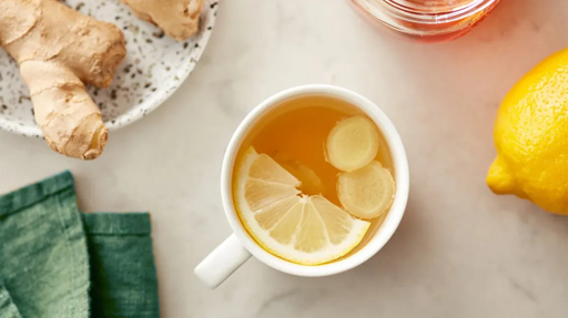 Tasse de tisane au gingembre tenue par une femme enceinte, sans visage visible