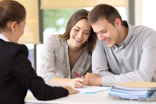 Couple signing closing documents with their real estate agent