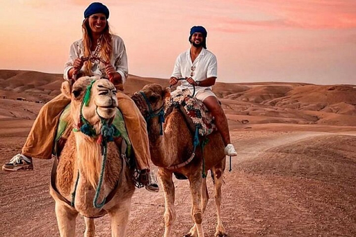 Couple riding camels at sunset during a private Agafay Desert tour from Marrakech