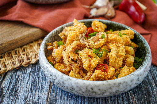 Golden-brown salt and pepper squid garnished with chilli and spring onion, a Cantonese seafood dish
