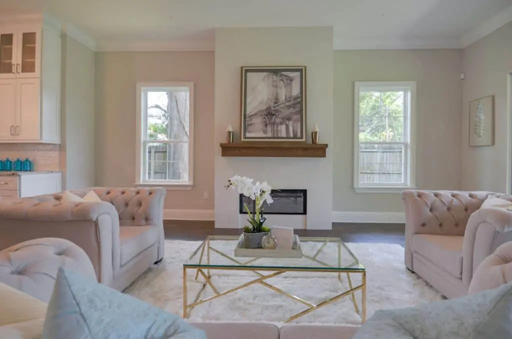 Professionally staged living room with symmetrical sofas, coffee table, and fireplace