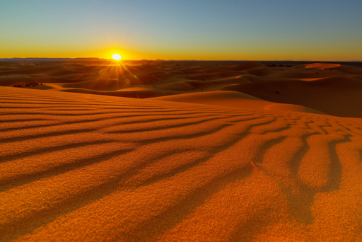 Erg Chebbi desert dunes and camel caravan at sunset in Merzouga Morocco