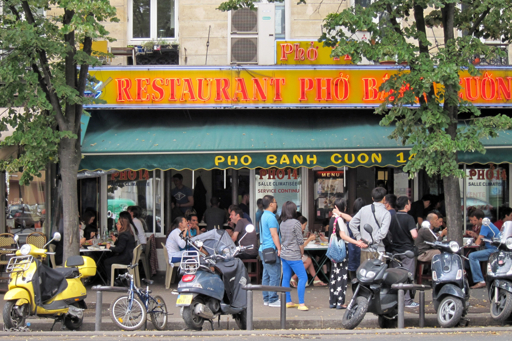Vietnamese restaurant "PHO BANH CUON 1" in Paris, serving phở and bánh cuốn, with customers seated at sidewalk tables.