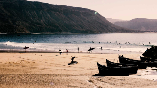 Taghazout Morocco surf beach with surfers and fishing boats on the Atlantic coast