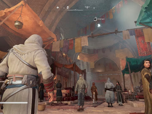 A screenshot from the video game Assassin’s Creed Mirage showing the protagonist Basim in a white hooded robe standing in a bustling medieval Baghdad marketplace with colorful banners, market stalls, and various NPCs.