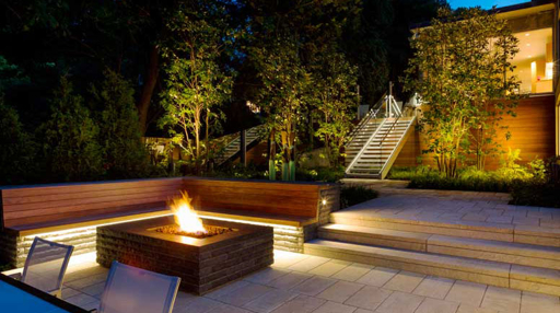 Professionally lit home exterior at night with landscape lighting