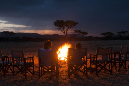 Campfire at a Serengeti tented camp at dusk