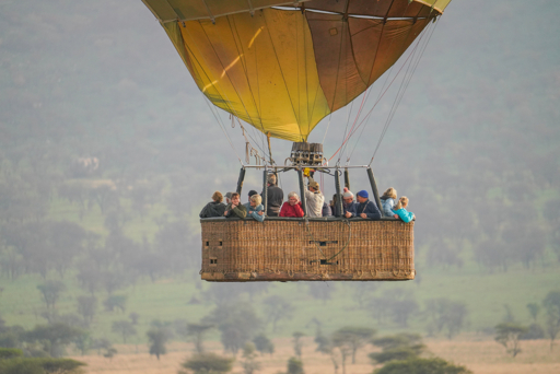 Hot air balloon basket with passengers over the Serengeti at sunrise