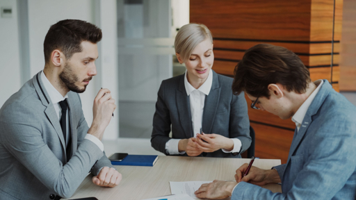 Trois professionnels en réunion de travail autour d'une table de bureau