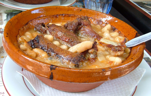 Cassoulet with white beans, meat, and sausage served in an earthenware bowl.