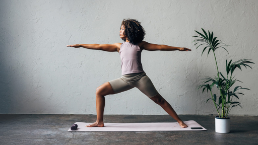 Woman practicing Warrior II yoga pose in a studio