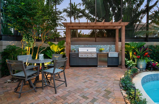 Outdoor kitchen with grill and poolside dining area