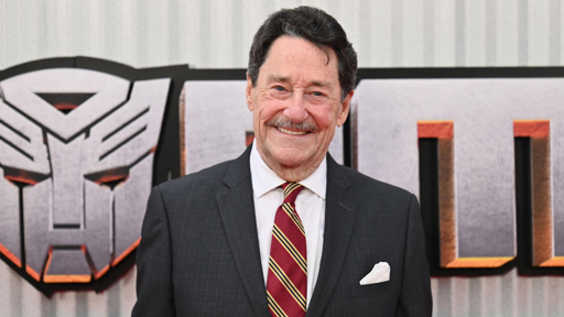 Peter Cullen frente a un fondo de Transformers