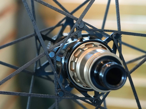 Close-up of a bicycle wheel hub and carbon-spoke connections, illustrating a specialized wheel construction.
