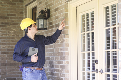 Home inspector pointing at the exterior of a house while inspecting it