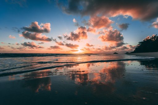 Warm sunset light reflected across ocean waves and a sandy beach